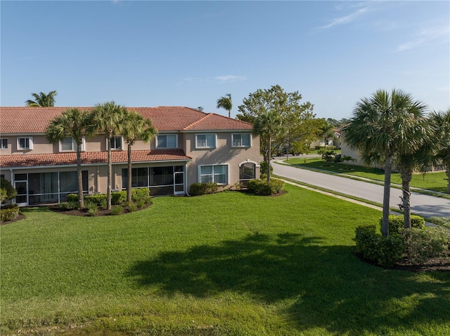 mediterranean / spanish house with a front yard and a sunroom