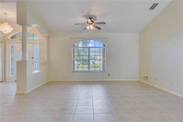 tiled empty room featuring ceiling fan with notable chandelier and ornate columns