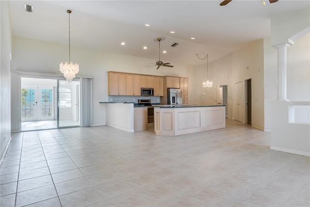 kitchen featuring appliances with stainless steel finishes, ceiling fan with notable chandelier, light brown cabinets, a high ceiling, and ornate columns