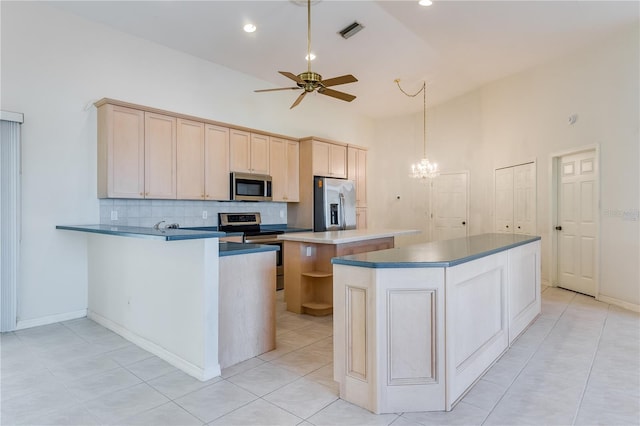 kitchen with ceiling fan with notable chandelier, high vaulted ceiling, stainless steel appliances, light tile floors, and a kitchen island