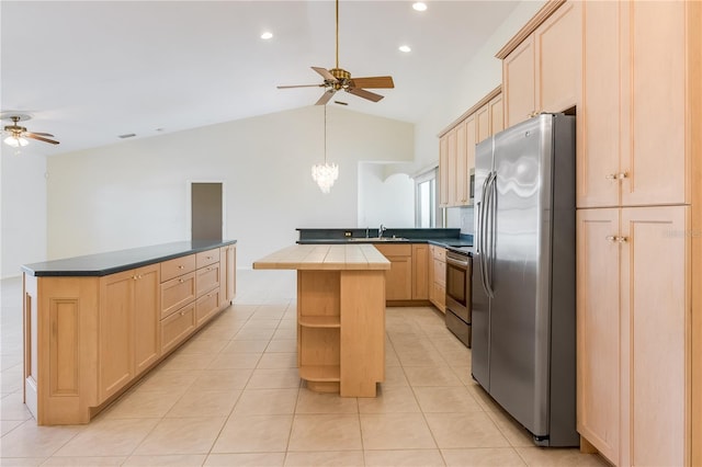 kitchen featuring appliances with stainless steel finishes, light tile flooring, light brown cabinets, ceiling fan with notable chandelier, and a center island