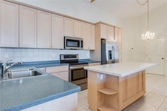 kitchen featuring sink, a kitchen island, appliances with stainless steel finishes, backsplash, and a notable chandelier