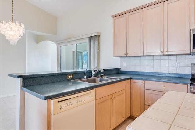 kitchen with white dishwasher, light brown cabinets, a notable chandelier, and sink