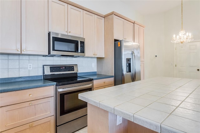 kitchen with decorative light fixtures, an inviting chandelier, light brown cabinets, tasteful backsplash, and stainless steel appliances