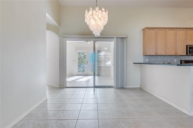 interior space featuring light tile flooring, french doors, and ceiling fan with notable chandelier