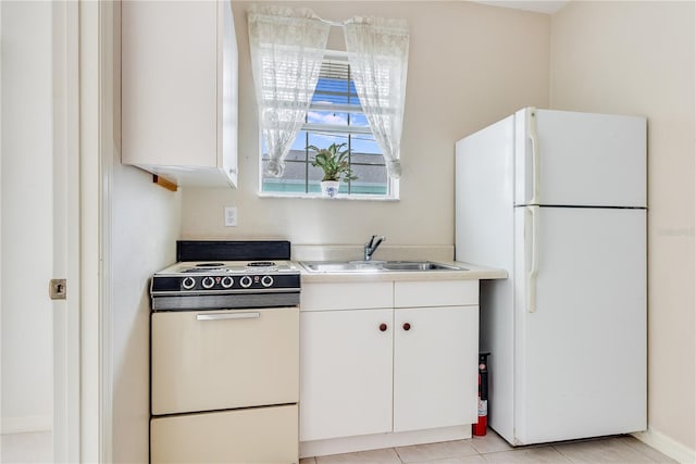 kitchen with light tile flooring, white appliances, white cabinetry, and sink