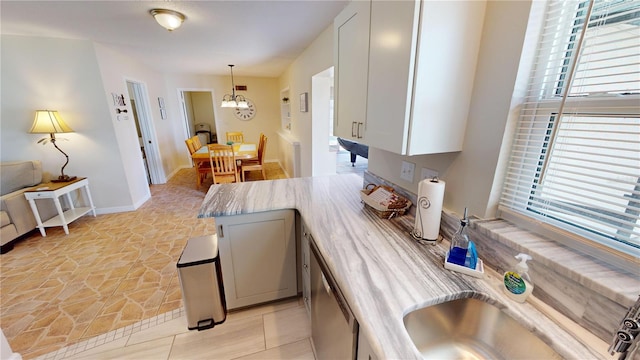 kitchen featuring decorative light fixtures, sink, light tile floors, white cabinets, and a chandelier