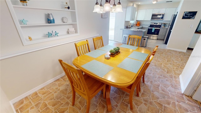 dining space featuring built in shelves, a notable chandelier, and sink