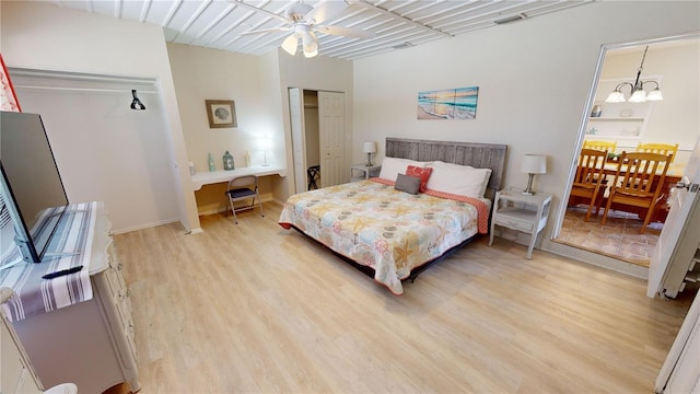 bedroom with light hardwood / wood-style floors and ceiling fan with notable chandelier