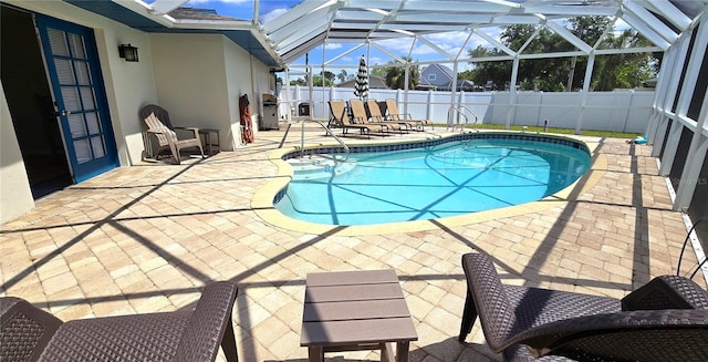 view of pool with glass enclosure and a patio area