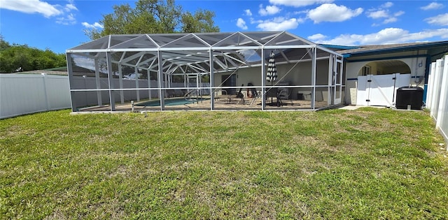 back of property featuring glass enclosure, a yard, a fenced in pool, and a patio area