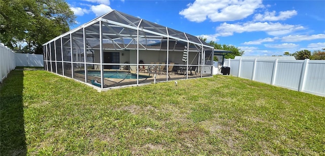 back of property with glass enclosure, a yard, and a fenced in pool