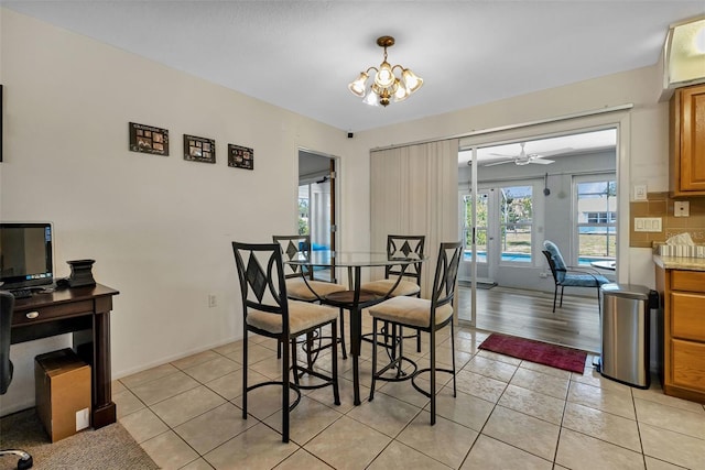 tiled dining space with ceiling fan with notable chandelier