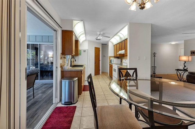 kitchen with sink, white appliances, ceiling fan with notable chandelier, and light tile patterned floors