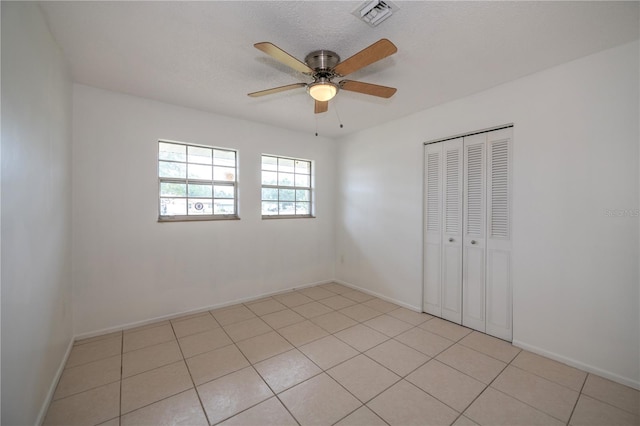 unfurnished room featuring light tile patterned floors, a textured ceiling, and ceiling fan