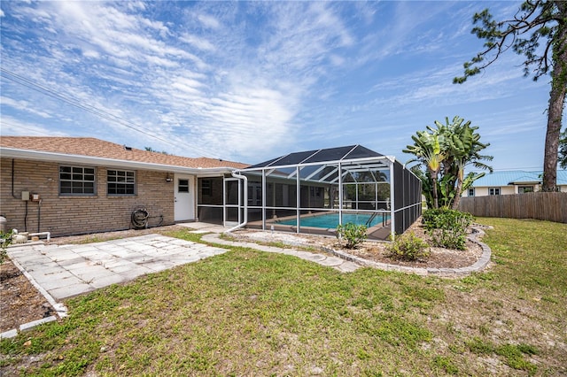 back of property featuring a fenced in pool, glass enclosure, a patio area, and a lawn