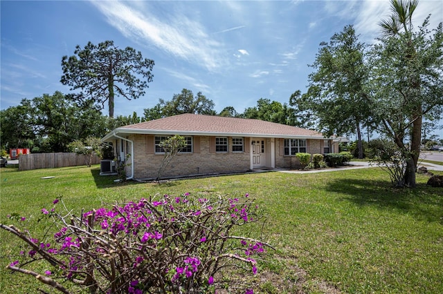 ranch-style home featuring cooling unit and a front lawn