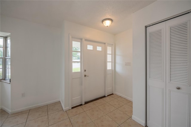 foyer entrance with light tile patterned flooring and a textured ceiling