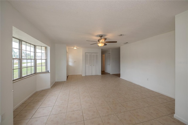 unfurnished room with ceiling fan, light tile patterned floors, and a textured ceiling