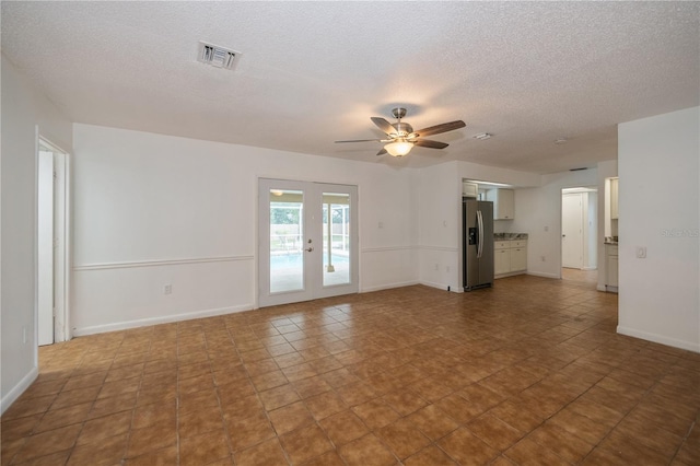 unfurnished living room with tile patterned floors, ceiling fan, a textured ceiling, and french doors