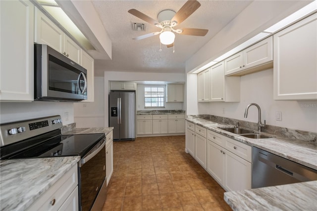 kitchen featuring a textured ceiling, stainless steel appliances, white cabinetry, and sink