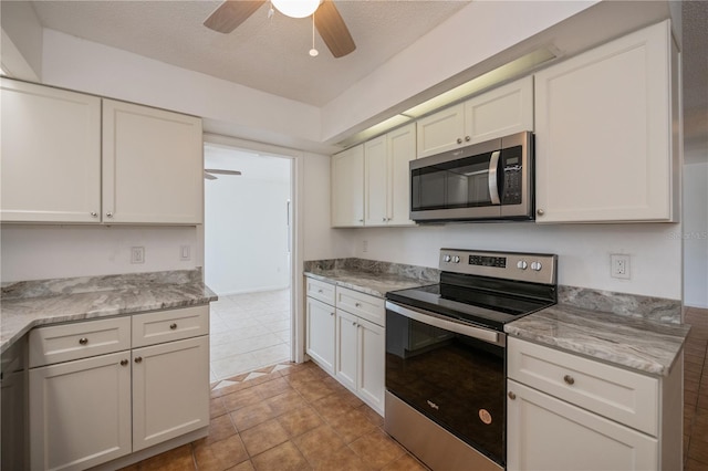 kitchen featuring ceiling fan, light stone counters, a textured ceiling, white cabinets, and appliances with stainless steel finishes