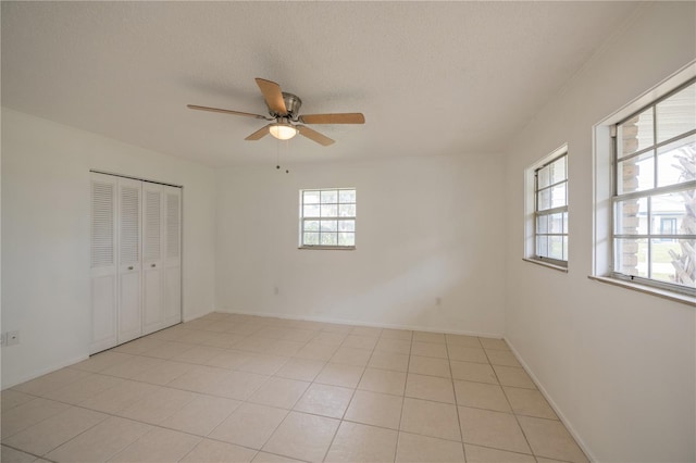 tiled empty room featuring a wealth of natural light, ceiling fan, and a textured ceiling