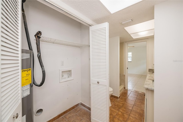 clothes washing area with hookup for a washing machine, dark tile patterned flooring, and a textured ceiling