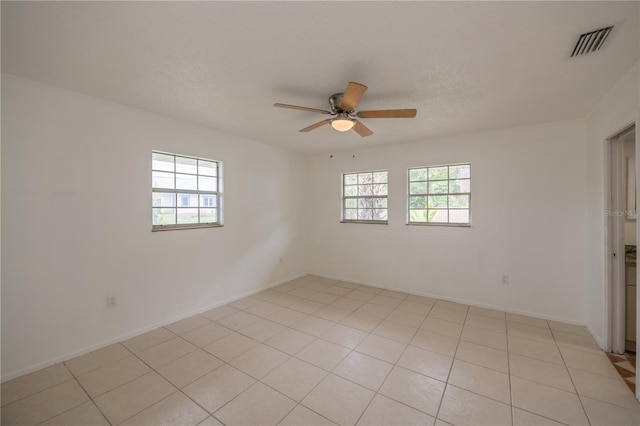 tiled empty room with ceiling fan, a healthy amount of sunlight, and a textured ceiling