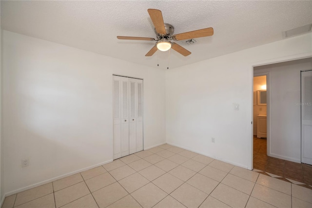 tiled empty room featuring ceiling fan and a textured ceiling