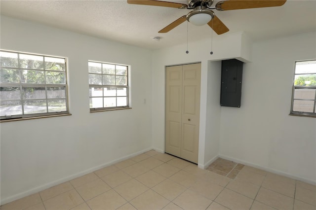 unfurnished bedroom with ceiling fan, light tile patterned floors, electric panel, and a closet