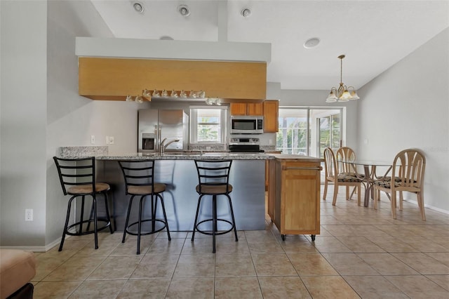 kitchen featuring decorative light fixtures, appliances with stainless steel finishes, a notable chandelier, light tile floors, and light stone counters