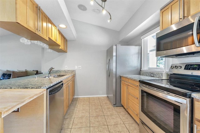 kitchen featuring appliances with stainless steel finishes, track lighting, light stone countertops, sink, and light tile flooring