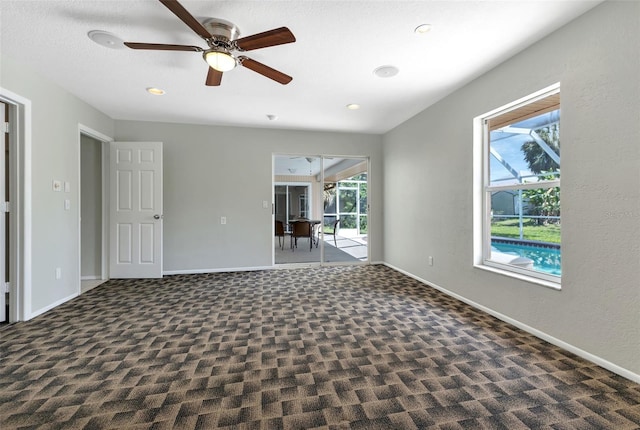 empty room featuring ceiling fan and dark colored carpet