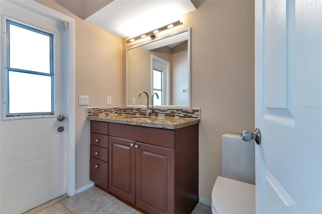 bathroom with toilet, tile floors, a wealth of natural light, tasteful backsplash, and large vanity