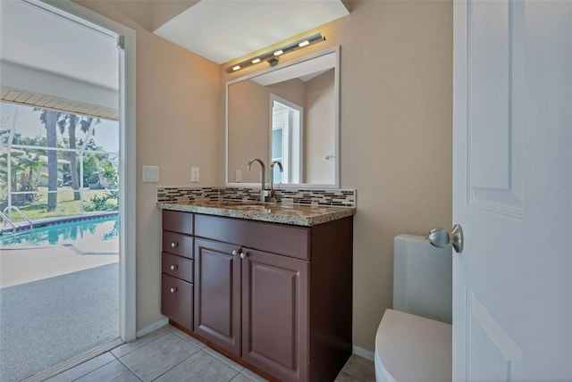 bathroom with toilet, tile flooring, large vanity, and tasteful backsplash