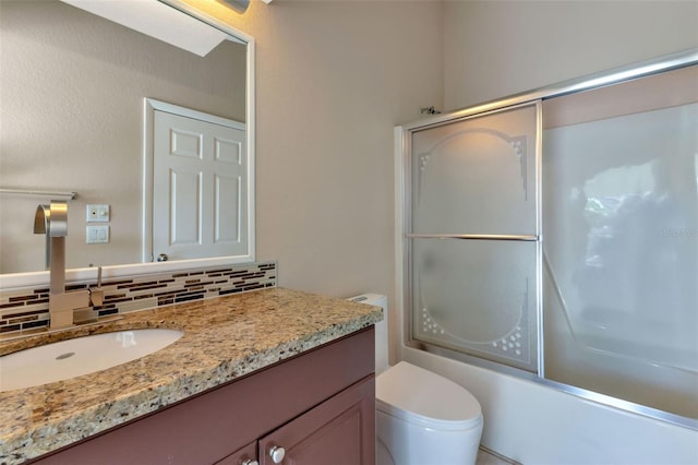 full bathroom featuring large vanity, toilet, tasteful backsplash, and combined bath / shower with glass door