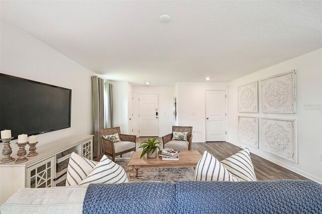 living room with a textured ceiling and dark hardwood / wood-style floors