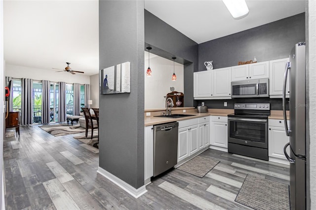 kitchen featuring stainless steel appliances, ceiling fan, sink, pendant lighting, and white cabinets