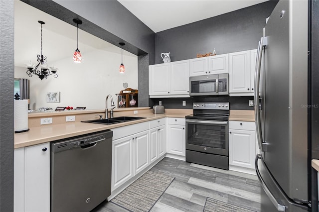 kitchen featuring white cabinetry, sink, light hardwood / wood-style flooring, pendant lighting, and appliances with stainless steel finishes