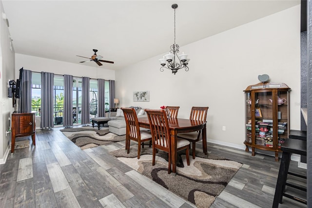 dining space with ceiling fan with notable chandelier and dark hardwood / wood-style flooring