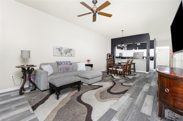 living room with ceiling fan with notable chandelier and hardwood / wood-style flooring