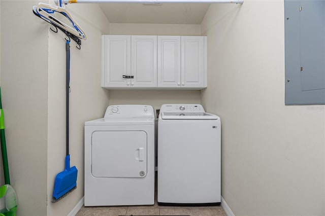 washroom featuring electric panel, washer and clothes dryer, light tile patterned flooring, and cabinets