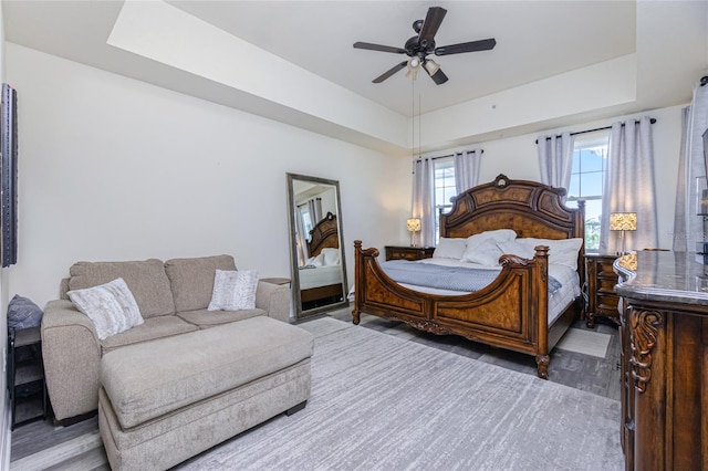 bedroom with wood-type flooring, a tray ceiling, and ceiling fan