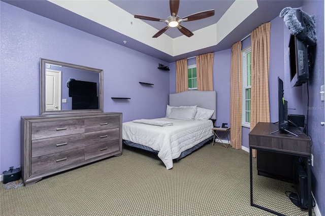 bedroom with carpet flooring, a raised ceiling, and ceiling fan