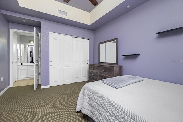 bedroom featuring ceiling fan, ensuite bath, carpet floors, and a closet