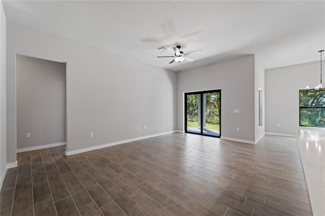 spare room with ceiling fan with notable chandelier and dark hardwood / wood-style flooring