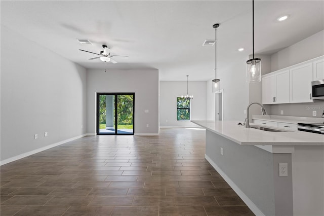 kitchen with ceiling fan with notable chandelier, stainless steel appliances, hanging light fixtures, sink, and white cabinetry