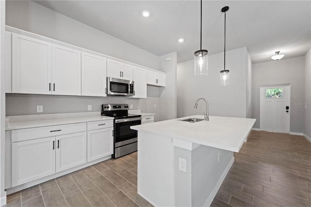 kitchen featuring sink, an island with sink, white cabinetry, stainless steel appliances, and decorative light fixtures