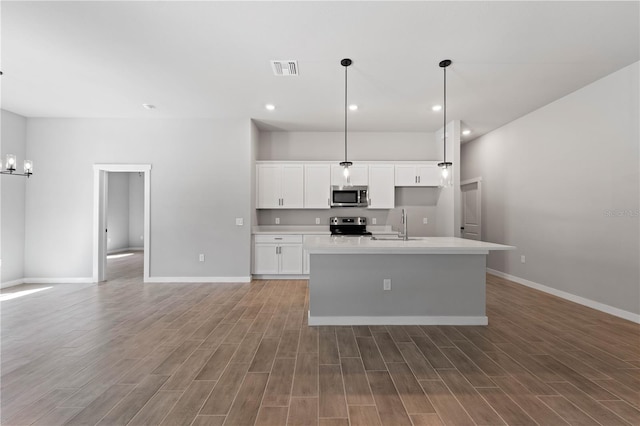 kitchen featuring hanging light fixtures, a kitchen island with sink, white cabinetry, appliances with stainless steel finishes, and dark hardwood / wood-style floors